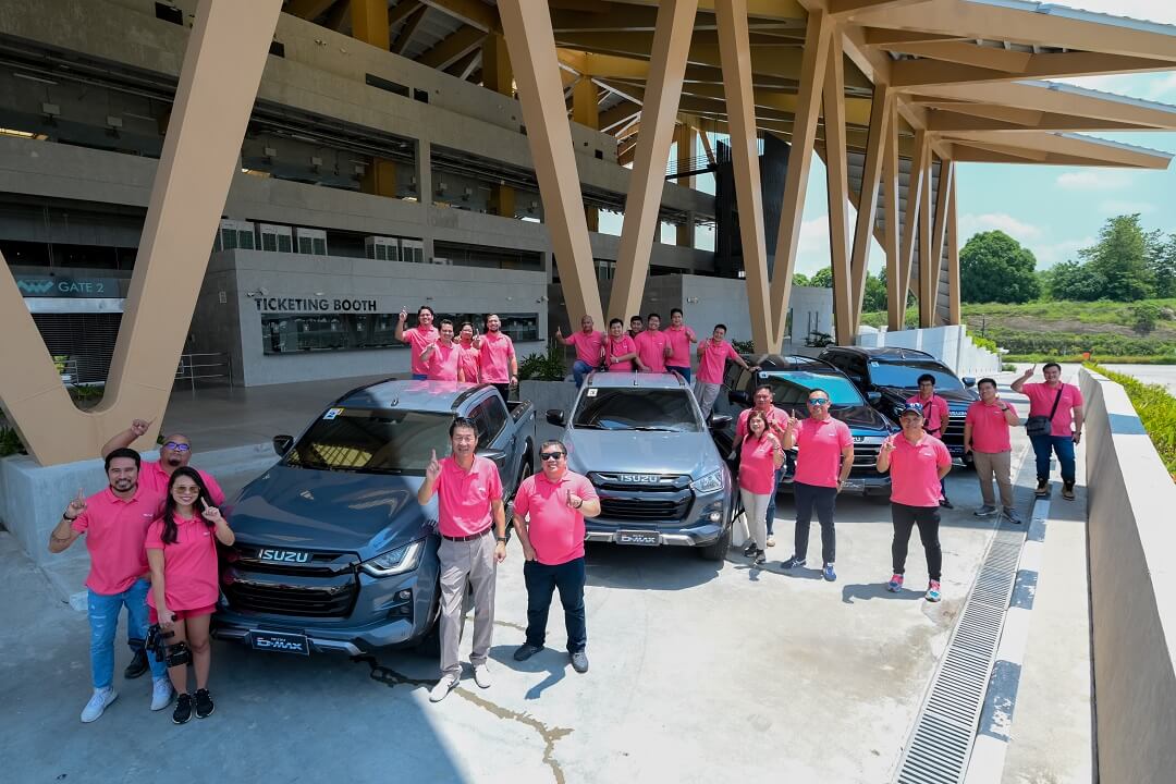 A group of people standing in front of cars

Description automatically generated with medium confidence